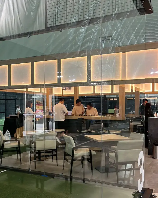 Players at the café seen through the glass of Court 3